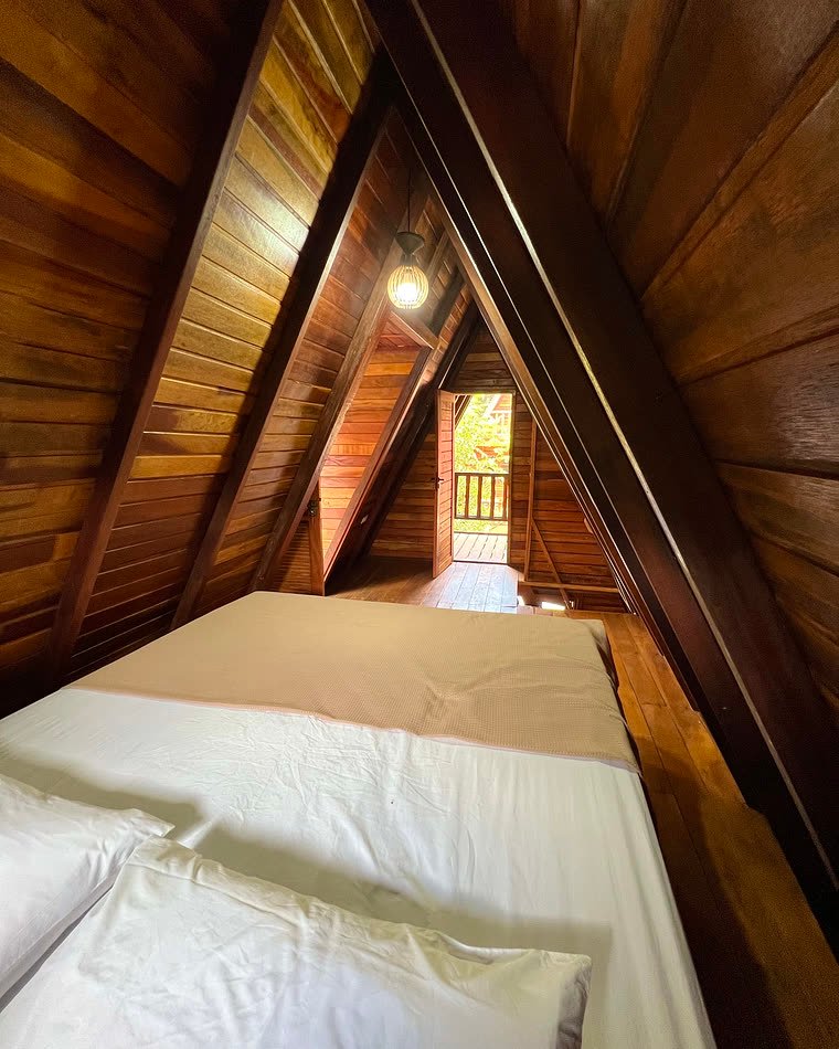 Cama arrumada no mezanino de madeira do chalé, em Lençóis